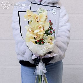 Букет из орхидеи желтой, астранции и красного гиперикума в бордовой пленке